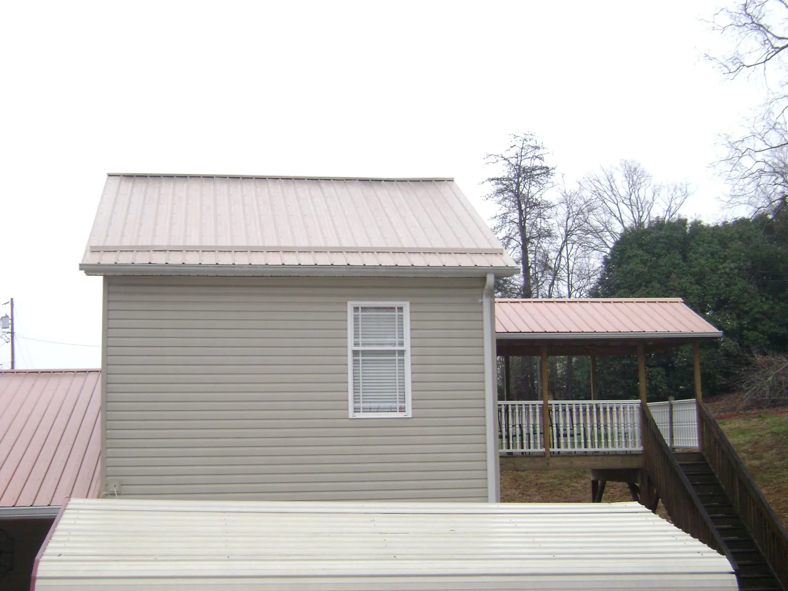 Tan metal roofs on a two story addition and attached porch, from a Roof Replacement job in Hermosa Beach